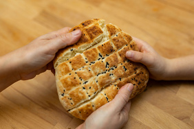 Drei Hände brechen ein Brot