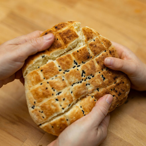 Drei Hände brechen ein Brot