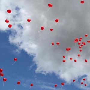 Rote Herzluftballons am blauen Himmel